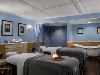 A serene spa room with two massage tables, soothing colors, and a relaxed ambiance