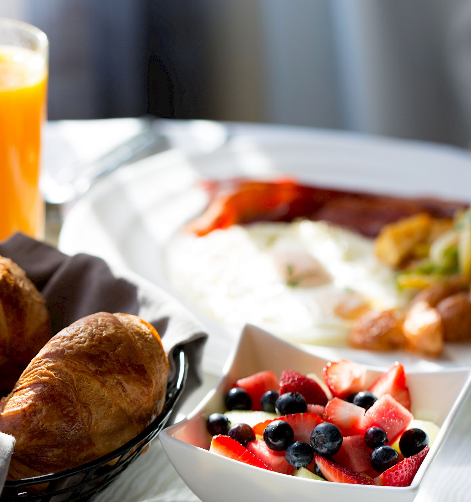A breakfast spread with croissants, fruit, and eggs.